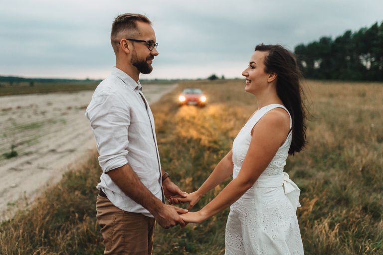 Para na tle samochodu i zachodzącego światła – romantyczna atmosfera